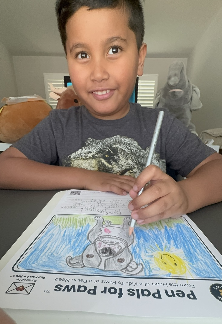 Krystian creating a Pen Pals for Paws letter for a shelter dog